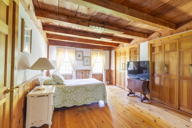 bedroom with light wood-type flooring, beamed ceiling, wooden walls, and wooden ceiling