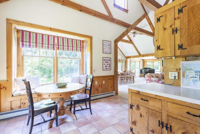 tiled dining space with ceiling fan, wooden walls, a baseboard radiator, and lofted ceiling with beams