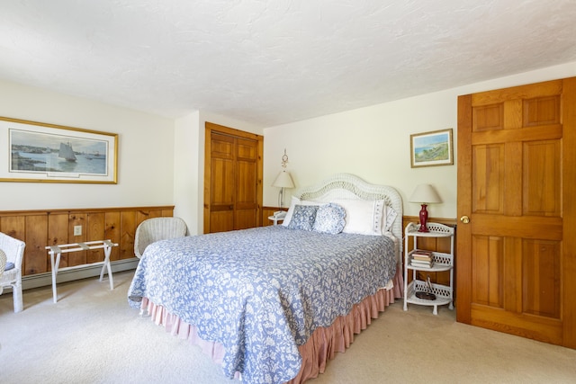 carpeted bedroom with a textured ceiling, a baseboard heating unit, and a closet