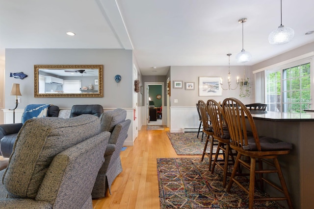 33 Rogers Rd, Brewster, MA 02631 - dining room featuring a chandelier, wainscoting, light wood-style floors, an AC wall unit, and a baseboard radiator