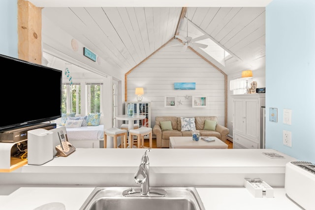 kitchen with lofted ceiling with skylight, sink, wood walls, wooden ceiling, and ceiling fan