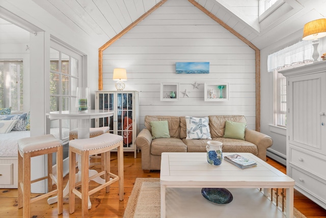 living room with vaulted ceiling, light wood-type flooring, and a baseboard heating unit