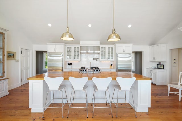 23 Oyster Pond Ln, Chatham, MA 02633 - kitchen featuring high end fridge, wall chimney exhaust hood, wood counters, tasteful backsplash, and lofted ceiling