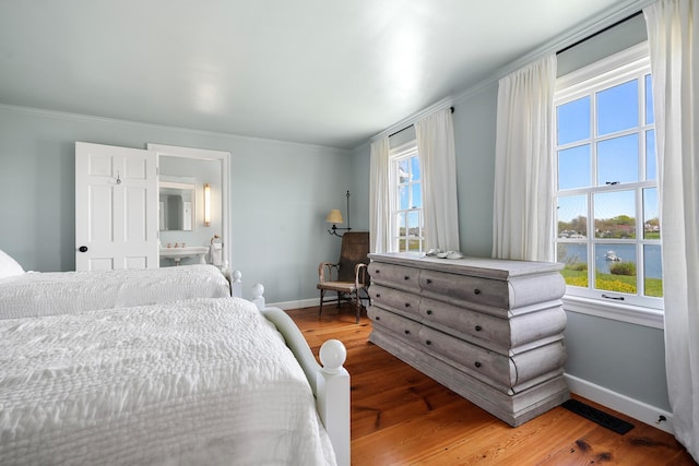 23 Oyster Pond Ln, Chatham, MA 02633 - bedroom with crown molding, wood finished floors, a water view, and connected bathroom
