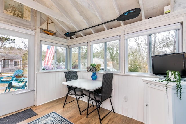 sunroom / solarium with wood finished floors, a wooden deck, lofted ceiling, and a healthy amount of sunlight