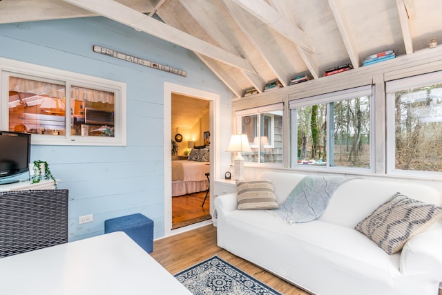 living area with lofted ceiling with beams, wood finished floors, and wood walls