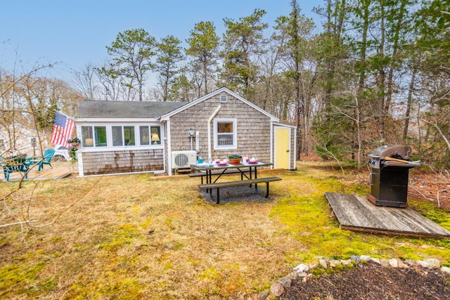 rear view of property featuring a lawn and ac unit