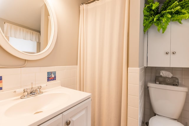 bathroom with vanity, toilet, tile walls, and a wainscoted wall