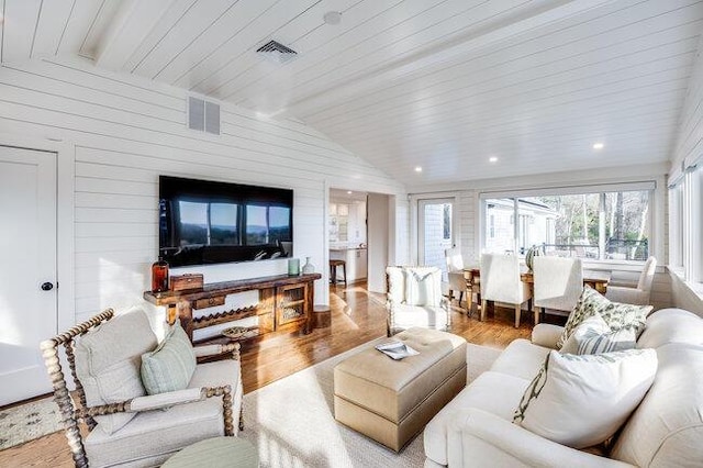 living room with visible vents, vaulted ceiling with beams, and wood finished floors