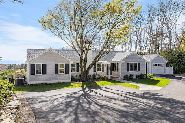 single story home with a front lawn, cooling unit, aphalt driveway, and a garage