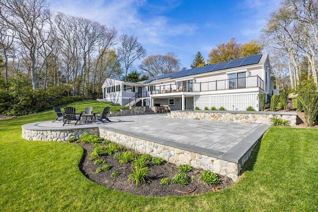 back of house with a yard, a patio, stairway, roof mounted solar panels, and a sunroom