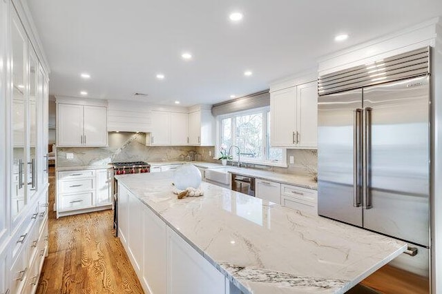 kitchen with a large island, white cabinetry, light wood-style flooring, and appliances with stainless steel finishes