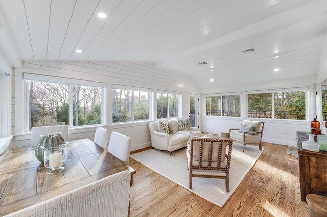 sunroom with a wealth of natural light, wood finished floors, and vaulted ceiling