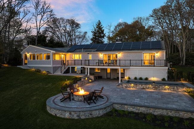 rear view of house featuring stairs, a fire pit, solar panels, a jacuzzi, and a lawn