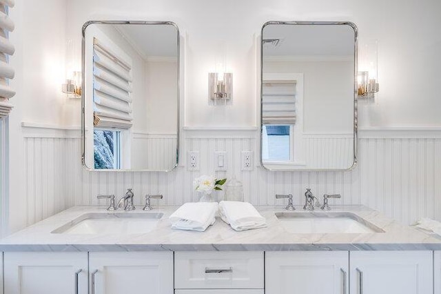 full bath with double vanity, wainscoting, and a sink