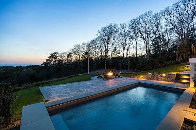 outdoor pool with a yard, a patio, and a fire pit