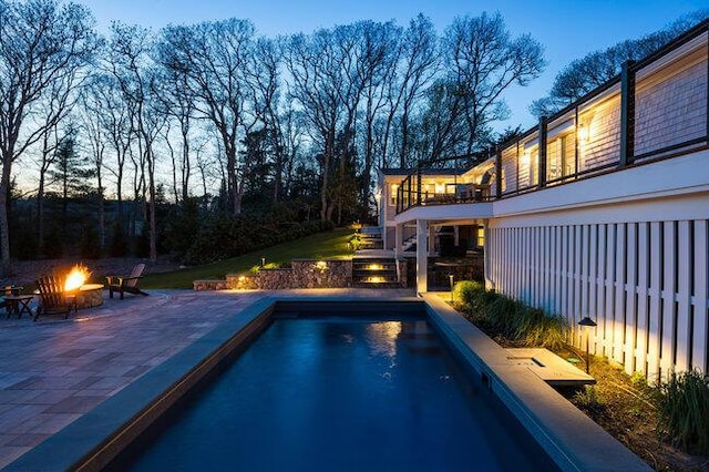 pool with a fire pit, a patio area, fence, and stairs