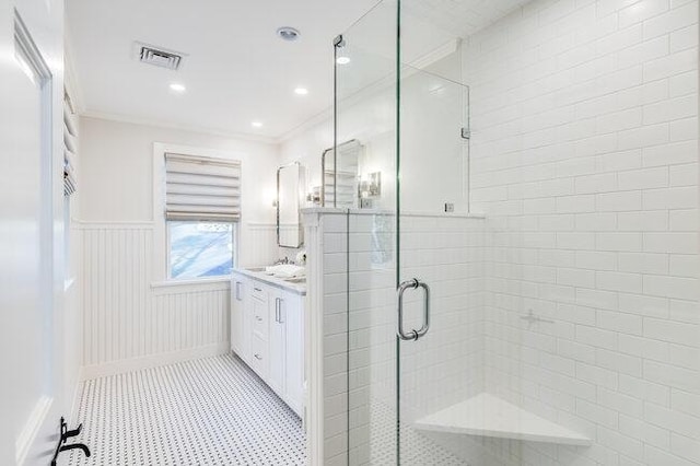 bathroom with a stall shower, a wainscoted wall, tile patterned floors, visible vents, and vanity