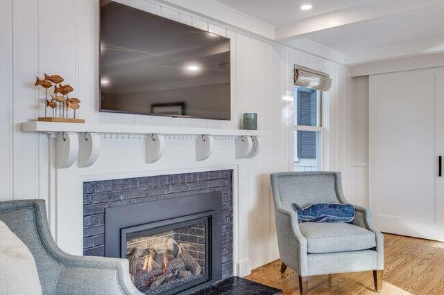 living area with a brick fireplace and wood finished floors