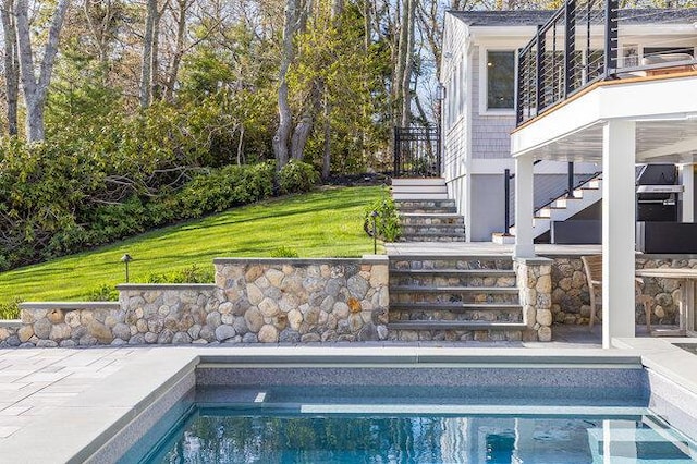outdoor pool with stairs and a lawn