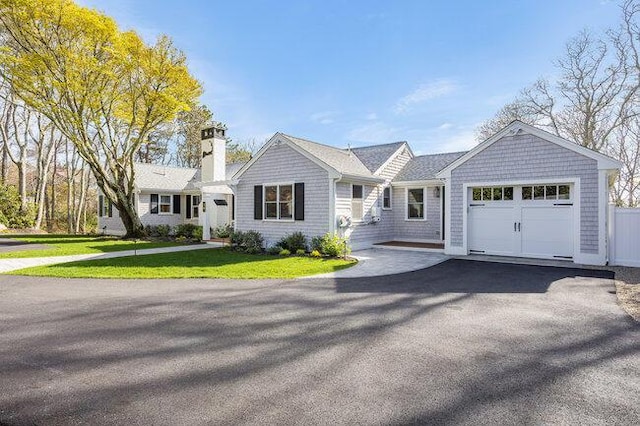 view of front of home with an attached garage, driveway, a chimney, and a front yard