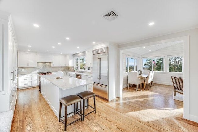 kitchen featuring plenty of natural light, visible vents, stainless steel built in refrigerator, and a kitchen island