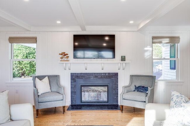 living area featuring a wealth of natural light, beam ceiling, and light wood-style floors