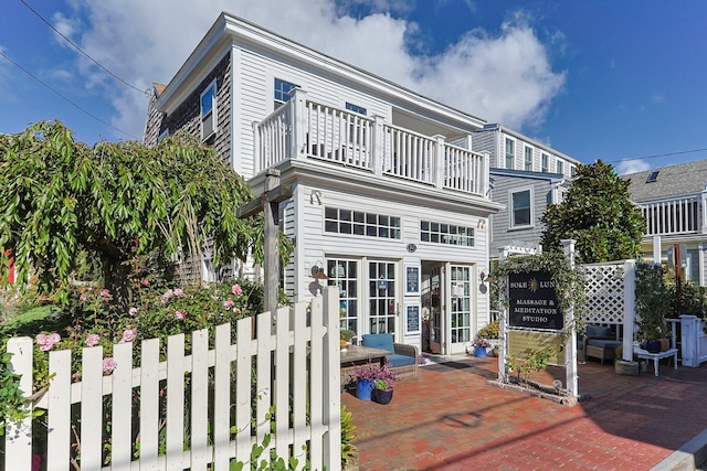 back of property with a balcony, french doors, and a patio