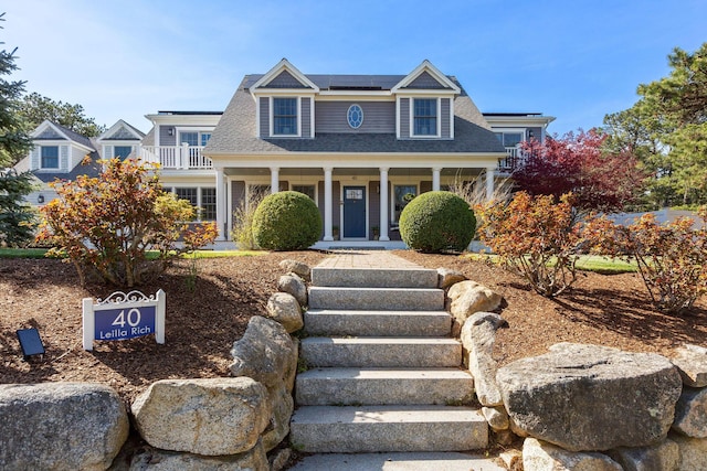 40 Leilla Rich Dr, Wellfleet, MA 02667 - view of front facade with a porch, roof mounted solar panels, stairs, a balcony, and a shingled roof