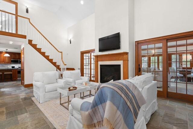 40 Leilla Rich Dr, Wellfleet, MA 02667 - living room featuring high vaulted ceiling, stone tile floors, a glass covered fireplace, baseboards, and stairs