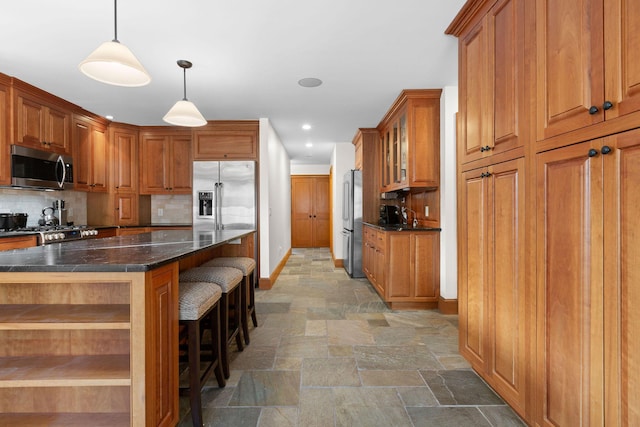 40 Leilla Rich Dr, Wellfleet, MA 02667 - kitchen featuring stainless steel appliances, stone tile floors, brown cabinetry, baseboards, and tasteful backsplash
