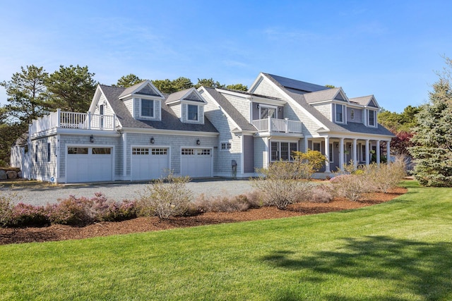 40 Leilla Rich Dr, Wellfleet, MA 02667 - shingle-style home featuring a balcony, an attached garage, a front yard, gravel driveway, and roof mounted solar panels