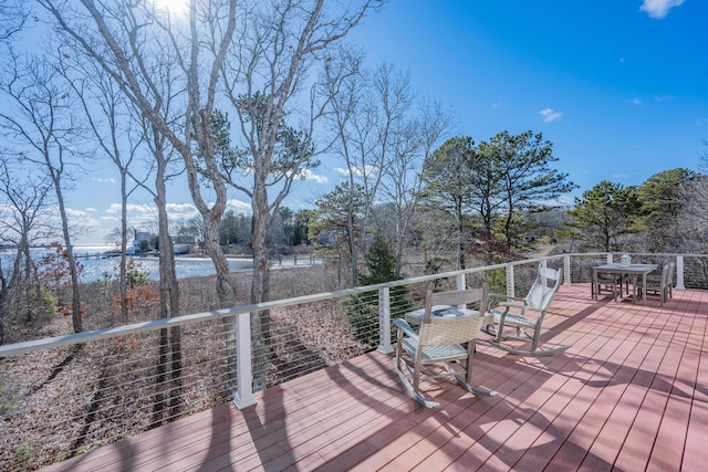 wooden terrace with outdoor dining space and a water view