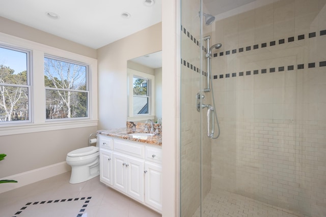 bathroom with toilet, a stall shower, vanity, baseboards, and tile patterned floors