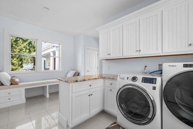 clothes washing area with light tile patterned floors, washer and clothes dryer, and cabinet space