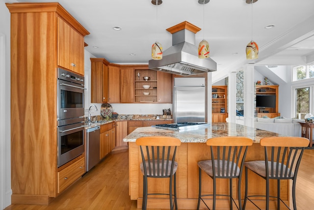 kitchen featuring island range hood, appliances with stainless steel finishes, open floor plan, hanging light fixtures, and open shelves