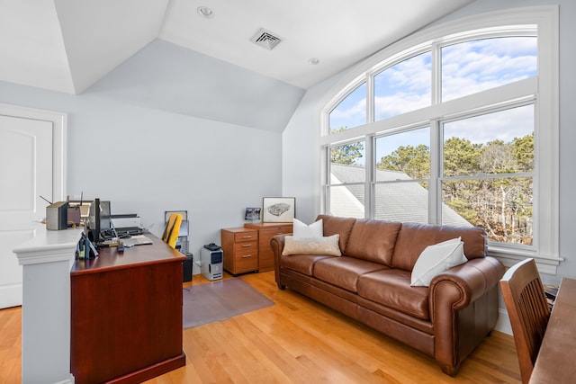 office with light wood-style floors, lofted ceiling, and visible vents