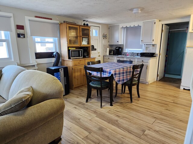 dining space with sink, light hardwood / wood-style flooring, and a textured ceiling