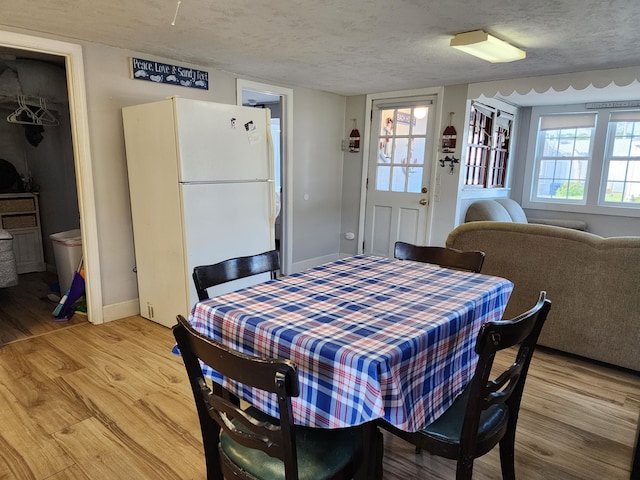 dining area with light wood-type flooring and a textured ceiling