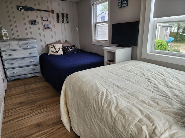 bedroom featuring dark hardwood / wood-style flooring and wooden walls