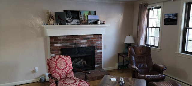 living room featuring hardwood / wood-style flooring, ornamental molding, a brick fireplace, and a baseboard heating unit