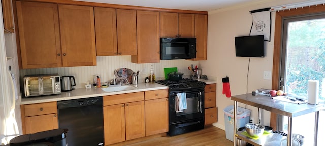 kitchen featuring ornamental molding, sink, light hardwood / wood-style floors, and black appliances