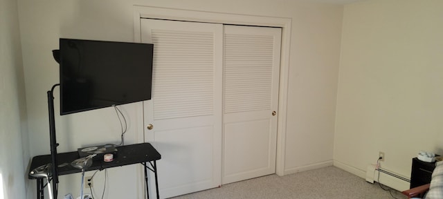 bedroom with a baseboard radiator, light colored carpet, and a closet