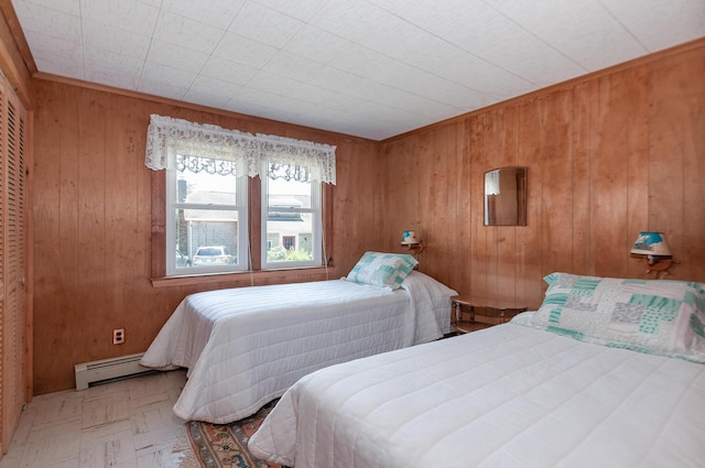 bedroom featuring baseboard heating and wood walls