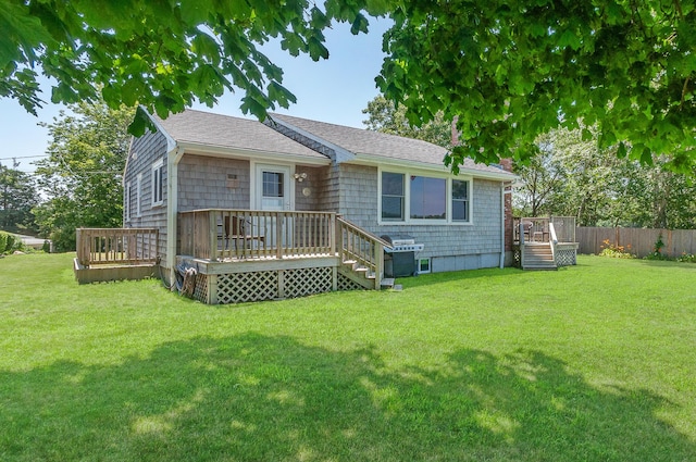 back of property with a deck and a lawn