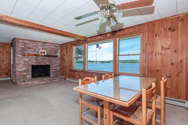 dining space with a water view, wood walls, a baseboard heating unit, and beamed ceiling