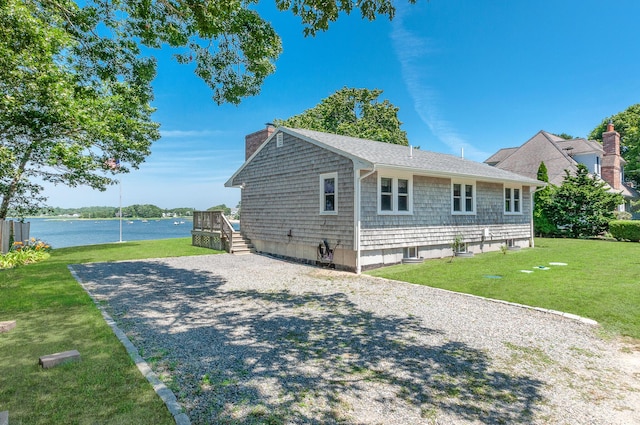 view of home's exterior featuring a deck with water view and a lawn