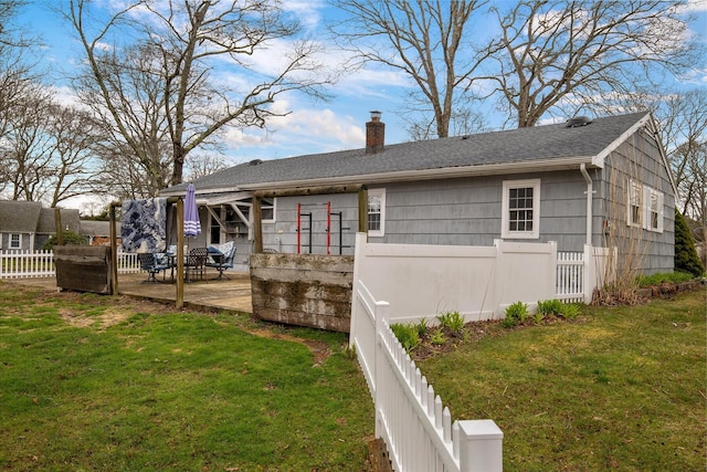 back of house with a shingled roof, a patio area, a lawn, a chimney, and fence
