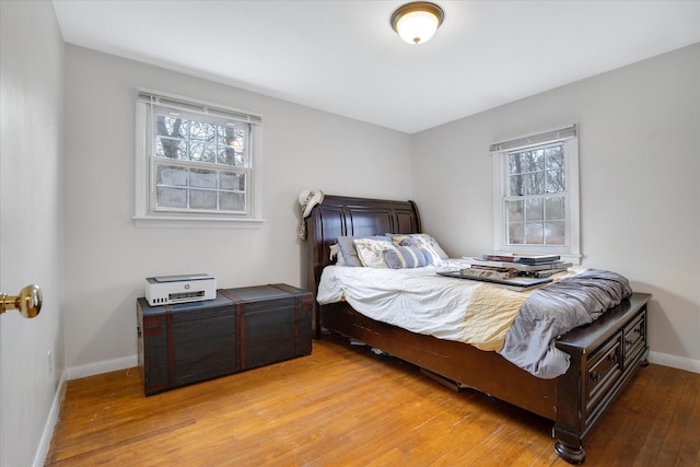 bedroom with light wood-style floors, multiple windows, and baseboards