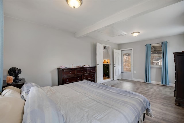 bedroom with beam ceiling, baseboards, and wood finished floors